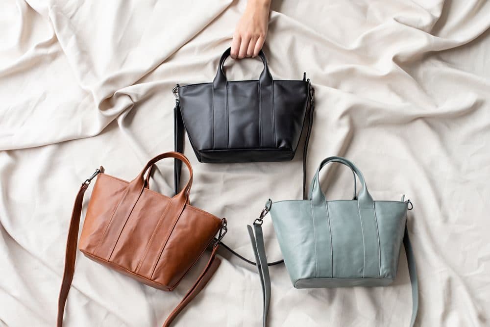Three leather tote bags laid out on a cream sheet